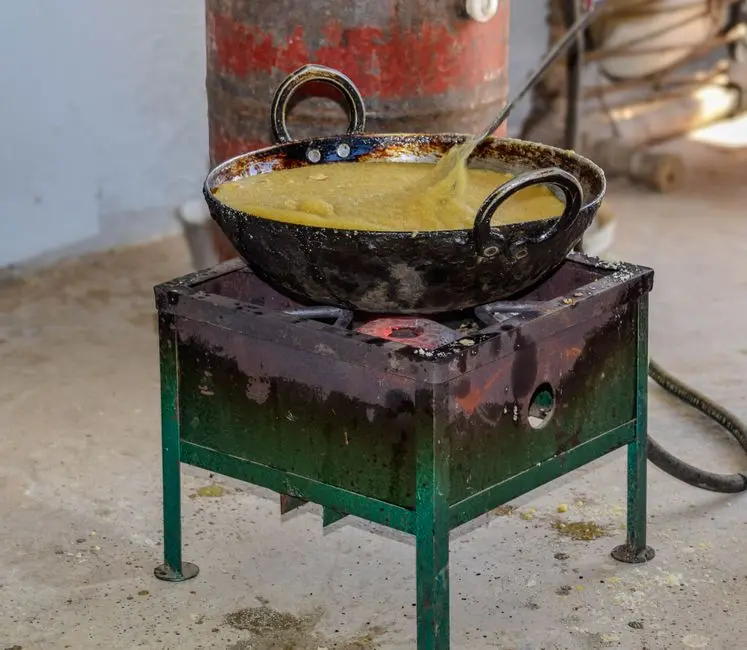 Proses memasak adonan pinyaram dalam wajan dengan latar dapur tradisional